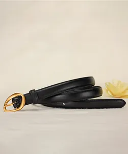 Detail of black leather belt with matte gold oval alloy buckle and fine stitching