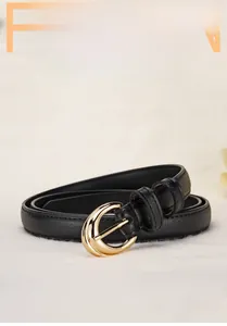 Detail of a thin black leather belt featuring a polished gold horseshoe-shaped alloy buckle