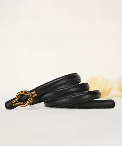 Dettaglio di sottile cintura in pelle nera con fibbia a nodo dorato e cuciture rifinite