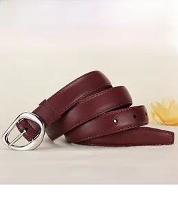 Detail of wine red leather belt with silver buckle on a soft cream fabric background