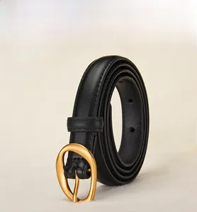 Detail of minimalist black leather belt with gold oval buckle and fine stitching