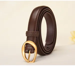 Detail of dark brown leather belt with matte gold horseshoe buckle and fine stitching