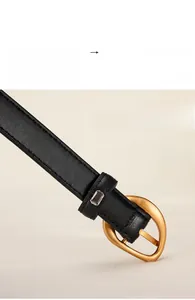Detailed close-up of a polished gold pin buckle on a textured black leather belt
