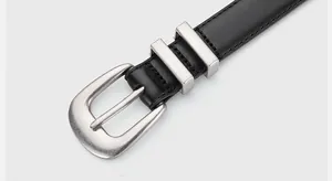 Detailed close-up of premium black leather belt with silver brushed metal pin buckle