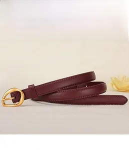 Detail of burgundy leather belt for women with golden horseshoe buckle on floral background