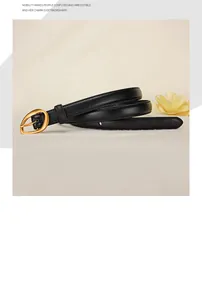 Detail of slim black leather belt with golden oval buckle on minimalist fabric background