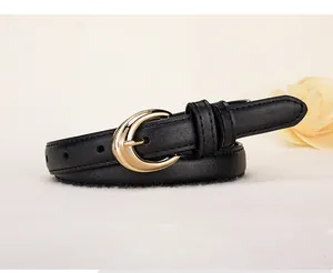 Close-up of narrow black leather belt with elegant crescent-shaped gold metal buckle