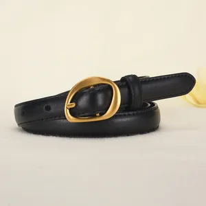 Women's vintage black leather belt with a minimalist matte gold oval buckle on beige fabric