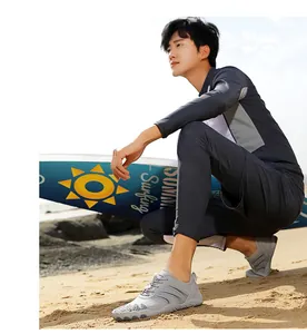 Close-up of breathable mesh water shoes on sand with sea and surfboard background