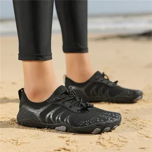 Schwarze Outdoor-Barfußschuhe mit Schnellverschlusssystem und rutschfester Sohle am Strand