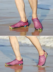Detalle de zapatos de agua de malla rosa con suelas antideslizantes en playa húmeda