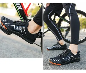 Detailed view of quick-lace system and orange grip sole on black outdoor sports shoes