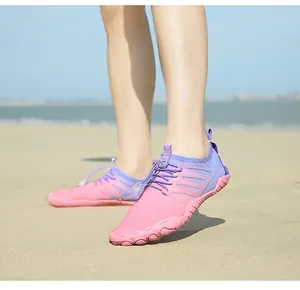 Scarpe acquatiche sfumate rosa viola con suole antiscivolo sulla spiaggia aperta
