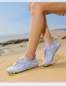 Close-up of violet water shoes with green details on a sandy beach setting