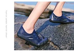 Détail de chaussures aquatiques bleu foncé avec lacets à cordon sur une plage rocheuse