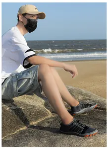 Détail de chaussures de plage respirantes en maille noire sur rochers avec semelle orange