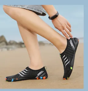 Dettaglio delle scarpe da scoglio nere traspiranti con suola colorata sulla spiaggia