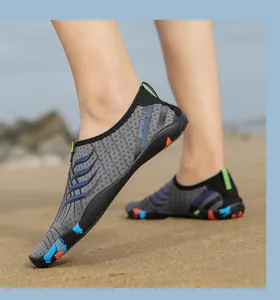 Dettaglio scarpe da scoglio grigie con onde blu su spiaggia, suola antiscivolo