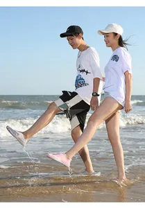 Pareja con zapatillas de agua de secado rápido en una playa soleada para nadar y caminar