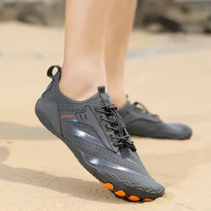 Detail of grey quick-dry water shoes with orange non-slip rubber sole on a sandy beach