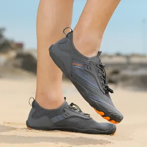 Detail of gray quick-dry barefoot water shoe with orange non-slip sole on sandy beach