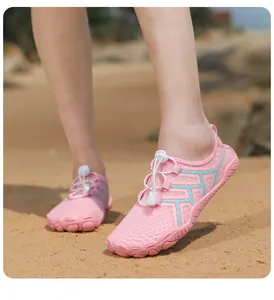 Scarpe acquatiche rosa ad asciugatura rapida con mesh traspirante su una spiaggia sabbiosa