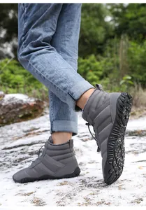 Outdoor shot of waterproof grey winter snow boots with thick faux fur lining on snowy rocks