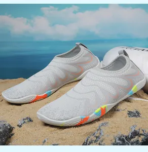 Détail de chaussures aquatiques gris clair avec semelle colorée sur une plage de sable