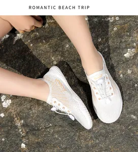 Close-up of white breathable mesh water shoes with orange accents on beach rocks