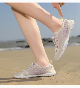 Detail of beige water shoe with purple mesh accents and quick-lace drawstring on the beach