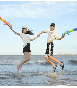 Pareja saltando en la playa usando zapatos de agua de secado rápido con pistolas de agua