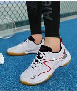 Détail de chaussures de badminton blanches respirantes avec accents rouges sur le terrain