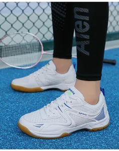 Détail de chaussure de badminton blanche avec semelle en gomme sur terrain de sport bleu