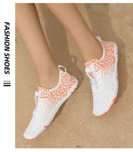 Detail of white and orange water shoes with quick-lace system and honeycomb pattern on sand