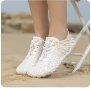 Primer plano de zapatos de agua blancos de secado rápido con ondas naranjas en la playa