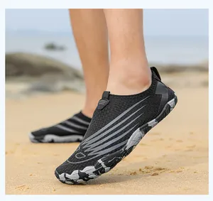 Close-up of black mesh water shoes with camouflage non-slip rubber soles on sand