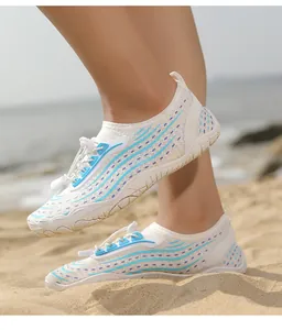 Primo piano di scarpe acquatiche in mesh bianco con motivi a onde blu-viola sulla sabbia