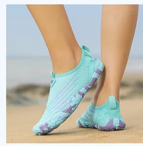 Detail of mint green aqua shoes with honeycomb mesh and purple non-slip sole on sand
