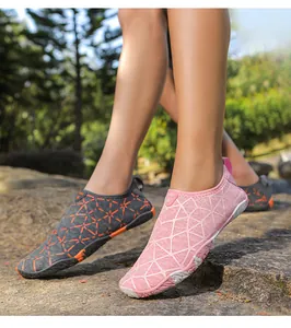 Primer plano de zapatos de agua transpirables rosa y gris sobre rocas de exterior