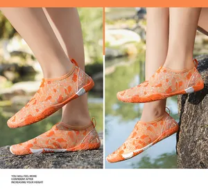 Oranje waterschoenen met marmerpatroon getoond op rotsen in een beekje buiten in de natuur