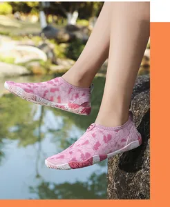 Detail van roze waterschoenen met bloemenpatroon en antislipzool op natte rotsen buiten