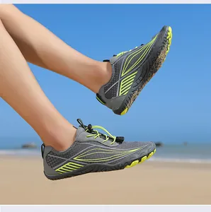 Detail of grey water shoes with green accents on sandy beach under sunny blue sky