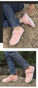 Detail view of pink kids barefoot shoes with breathable mesh and velcro on outdoor rocks