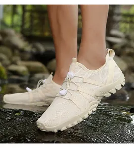 Detalle de zapato de agua blanco crema con malla transpirable sobre rocas de río mojadas