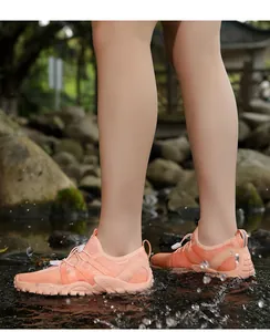 Detalle de zapato de agua rosa con orificios de drenaje y efecto salpicadura en arroyo