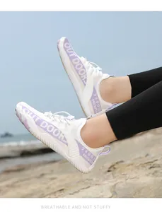 Atmungsaktive weiße Wasserschuhe mit lila Akzenten auf Strandfelsen mit Mesh-Gewebe