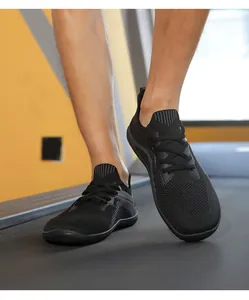 Close-up of black breathable mesh running shoes on a treadmill in a gym setting