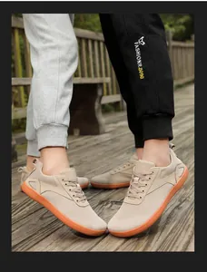 Close-up of khaki breathable mesh hiking shoes with orange rubber soles on a wooden path