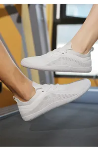 Macro side view of white breathable mesh barefoot running shoes on a gym treadmill