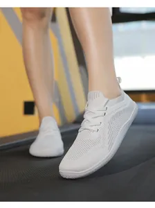 Close-up of white breathable flyknit running shoes on a gym treadmill for active training
